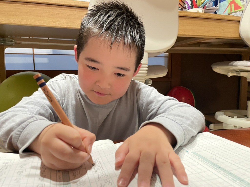 鉛筆を持ち、ノートに向かう子ども。